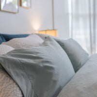 Picture of the head end of a soft comfortable bed, using six pillows and 3 sets of contrasting pi...