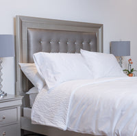 This is a photo of an elegant room scene featuring classic white-on-white bedding set off by a st...