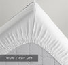 Underside of a mattress showing tight-elastic corners of a QuickZip Fitted SHeet. Caption "Won't Pop Off"