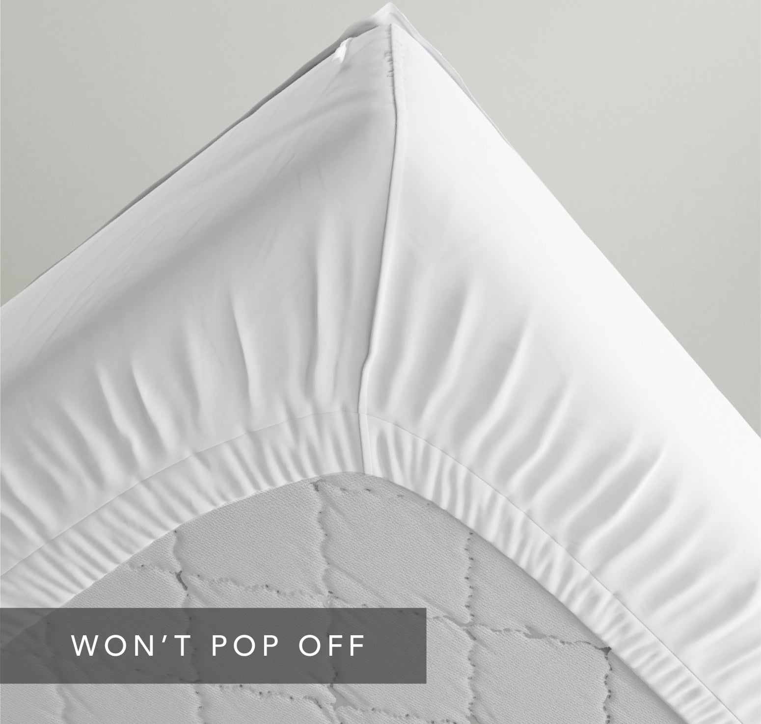 Underside of a mattress showing tight-elastic corners of a QuickZip Fitted SHeet. Caption "Won't Pop Off"
