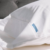 Sunlit photo of a white pillowcase, featuring the elegant finish detailing, including a folded fl...