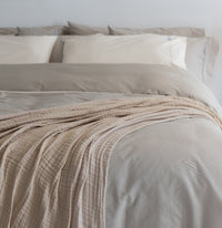This image shows a 100% cotton, gauze, muslin throw blanket on a bed styled with Sand Sateen Cott...